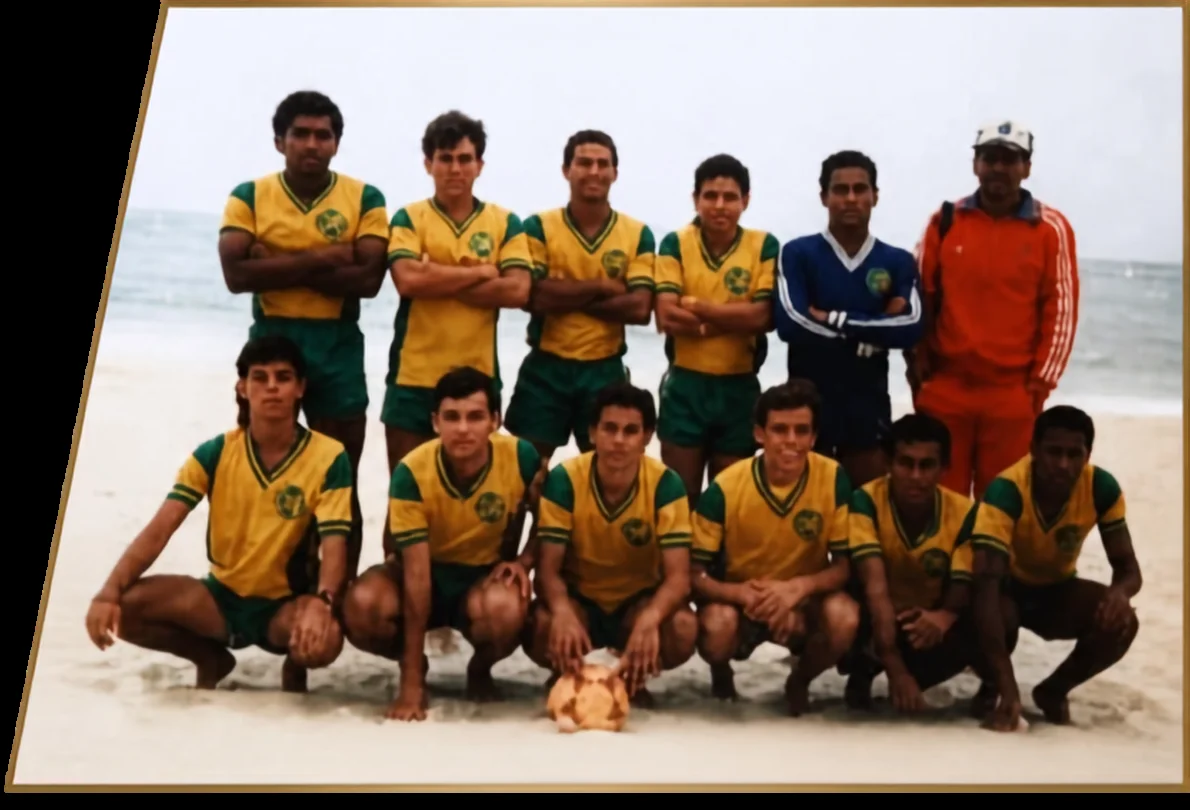 Grupo com uniformes amarelos e verdes, junto de outras pessoas, posando na areia.